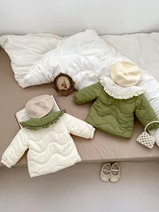 Detailed view of quilted cotton jackets for toddler girls with ruffled collars in green and white