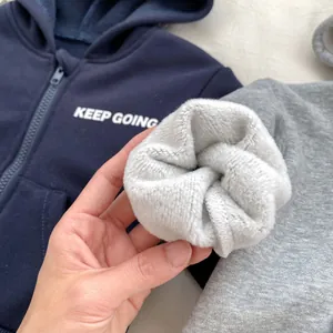 Detailed close-up of thick grey fleece lining inside a blue hooded sweatshirt for boys