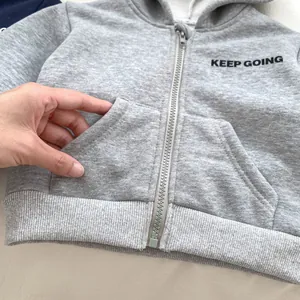 Detail view of the soft gray fabric texture and functional pockets on toddler hoodie