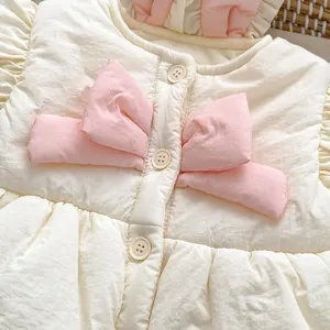 Gros plan sur le gilet matelassé pour bébé avec nœuds roses, col à volants et boutons