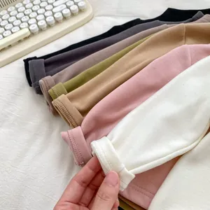Close-up of knit fabric texture and sewing detail on colorful toddler long sleeve shirts