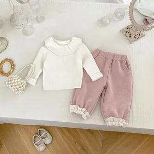 Girls 2-piece cream knit top with ruffle collar and pink pants featuring lace hem