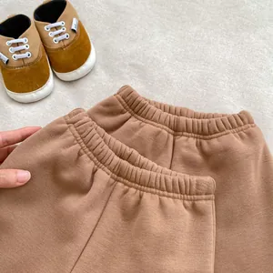 Vue détaillée de pantalons marron pour bébé avec taille élastique sur fond beige