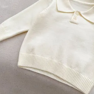 Detail of baby ivory knit polo sweater with turn-down collar and soft ribbed texture