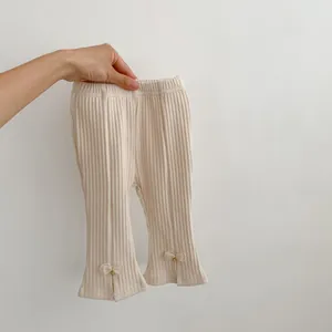 Dettaglio dei pantaloni in maglia a coste per neonati con fiocco e spacco laterale