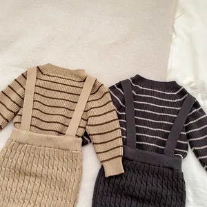 Detalle de conjuntos de punto para bebé con suéteres a rayas y pantalones de tirantes