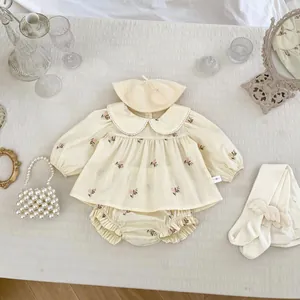 Dettaglio dell'outfit vintage da neonata con ricami e set coordinato di berretto in maglia