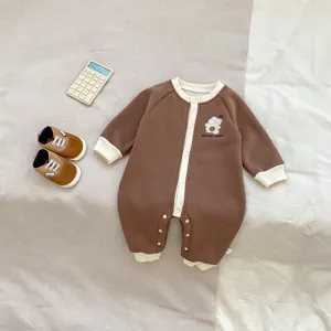 Détail de la barboteuse bébé avec broderie ours et fermeture à pression sur tissu