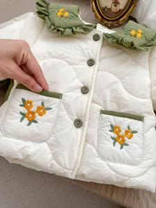 Detail of baby girls' quilted coat with green ruffle collar and floral embroidery motifs