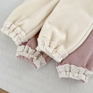 Detailed view of girls' ribbed knit cuffs with delicate white lace edges in pink and beige
