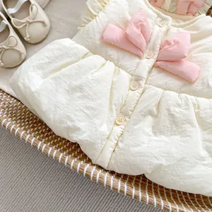 Vue détaillée du gilet matelassé pour bébé avec nœuds roses et volants dans un panier