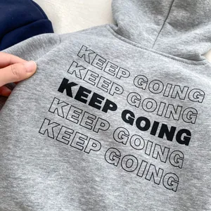 Detail shot of grey fleece hoodie showing the black Keep Going slogan print and soft texture