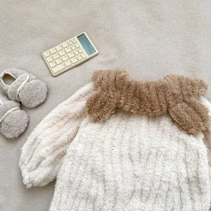 Detail of warm off-white fleece baby pajama set with brown collar and elastic cuffs