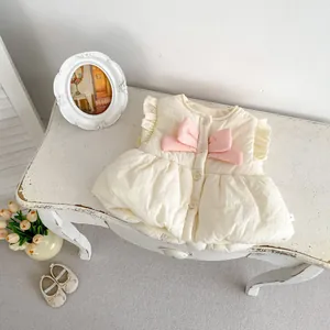 Détail du gilet matelassé crème pour bébé avec nœud rose, volants et boutons