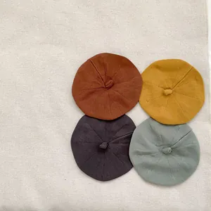 Flat lay of four colorful knitted baby beret hats in retro brown, yellow, purple, and green