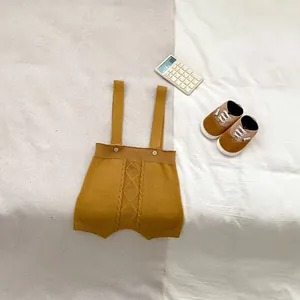 Close-up of mustard yellow knit baby overalls with rhombus texture and wooden buttons
