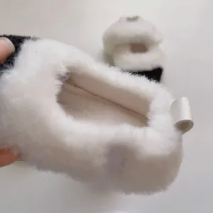 Détail de chaussons bébé en peluche avec texture douce et motif contrasté noir et blanc