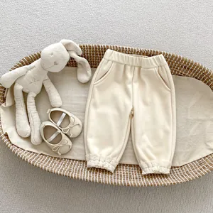 Detailed view of cream fleece pants for girls with delicate lace trim at the ankles