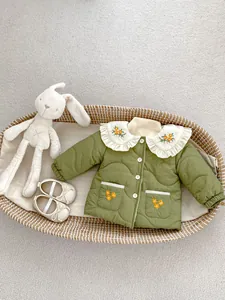 Detail of baby girl quilted olive jacket featuring white ruffle collar and floral embroidery