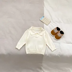 Detail of baby cream knit polo shirt with lapel collar and buttons on soft fabric
