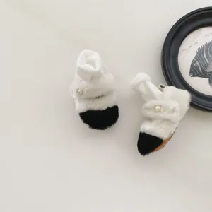Détail de chaussures en peluche pour bébé avec fausse fourrure bicolore et boucle perle