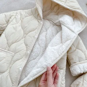 Dettaglio della tutina trapuntata per neonati color panna con morbida fodera in pile
