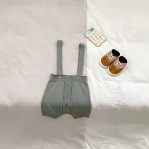 Detailed knit texture of sage green baby romper with cable pattern and wood buttons
