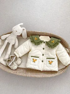 Detail of baby quilted jacket with green floral embroidered collar in a basket