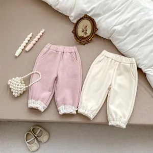 Detailed view of corduroy pants with elastic waist and delicate white lace cuffs