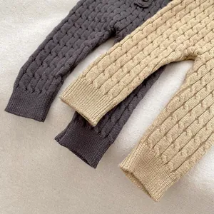 Detalle de pantalones de punto para bebé en gris y beige con trenzado para invierno