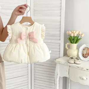 Détail du gilet matelassé fille avec nœud rose, volants et fermeture à boutons blancs