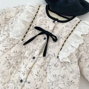Detailed view of baby quilted floral jumpsuit featuring lace edges and bow ties