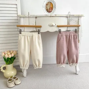 Detail of baby girls fleece trousers featuring lace hem and warm ribbed texture