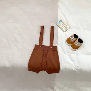 Detail of baby knit cable overall with wooden buttons and soft caramel yarn texture