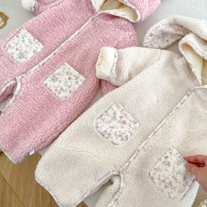 Detailed view of floral pockets and plush shearling texture on winter baby jumpsuits