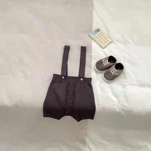 Flat lay of baby boy cable knit overalls in dark charcoal grey with wooden button detail