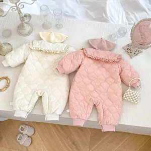 Flat lay of baby winter quilted rompers with delicate flower embroidery and beret hats
