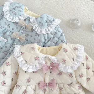 Detail of floral baby rompers with lace collar and pearl bow accent in blue and cream