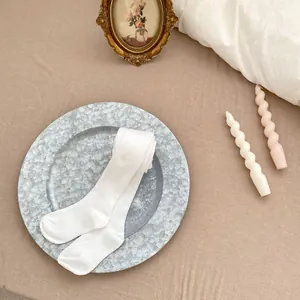 Détail de leggings pour bébé en coton blanc côtelé pliés sur un plateau en pierre
