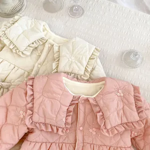 Detail of quilted baby romper featuring ruffled lace collar and rose flower embroidery