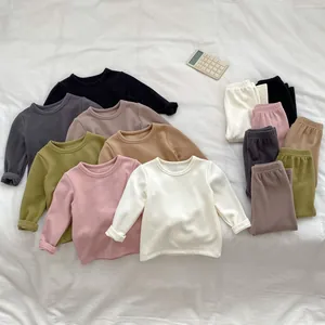Flat lay of soft autumn thermal baby loungewear sets in seven various solid colors