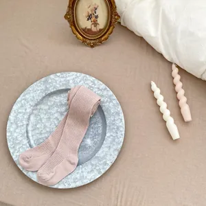 Détail de leggings côtelés roses pour bébé sur plateau avec décor chaleureux