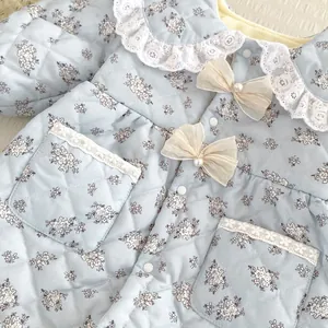 Detail of baby floral quilted romper with lace collar and pearl bow accents