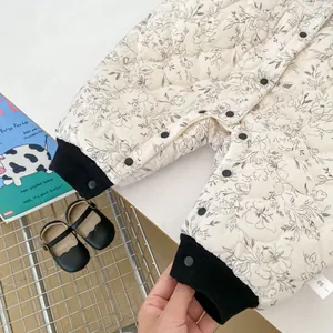 Detailed close-up of quilted floral infant romper with ribbed cuffs and size 66 label