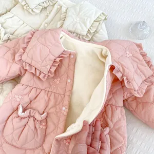 Detailed view of pink quilted fabric with floral embroidery and thick fleece lining
