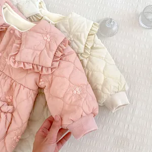 Close-up of quilted baby romper with delicate floral embroidery and ruffle collar
