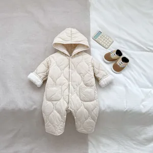 Dettaglio del motivo a rombi e della fodera in pile della tutina beige con cappuccio neonato