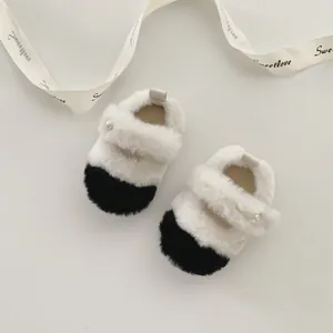 Détail de chaussures pelucheuses pour bébé en noir et blanc avec bouton perle élégant