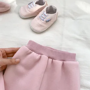 Detail of pink fleece pants with elastic waist and matching baby shoes for girls