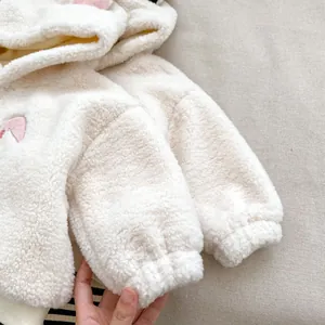 Nahaufnahme von weichem beigem Fleece-Baby-Hoodie mit niedlichen rosa Ohren-Details